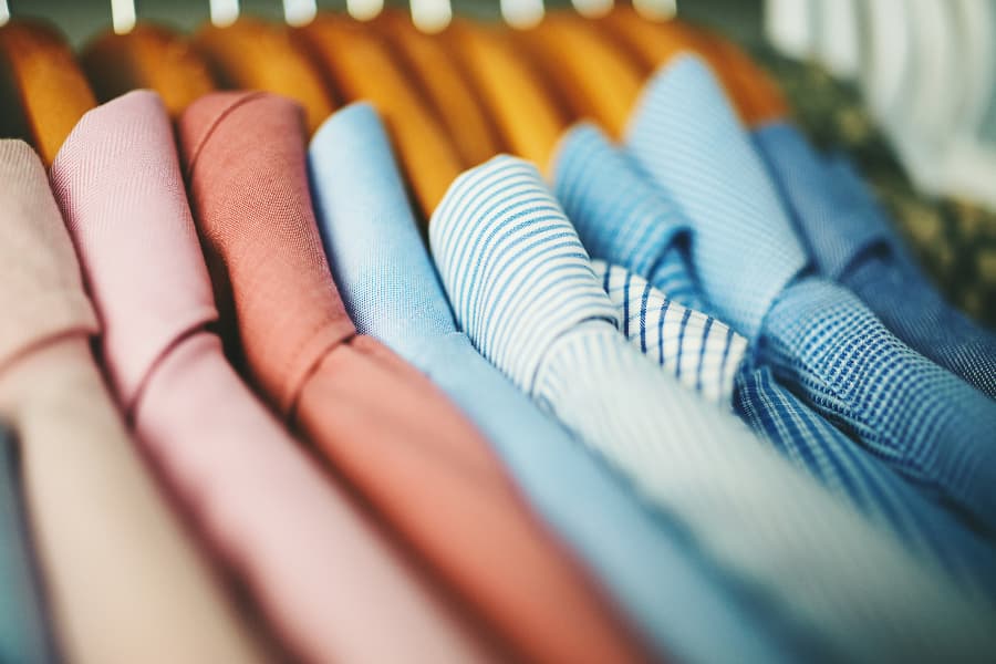 Assortment of men’s shirts on wooden hangers